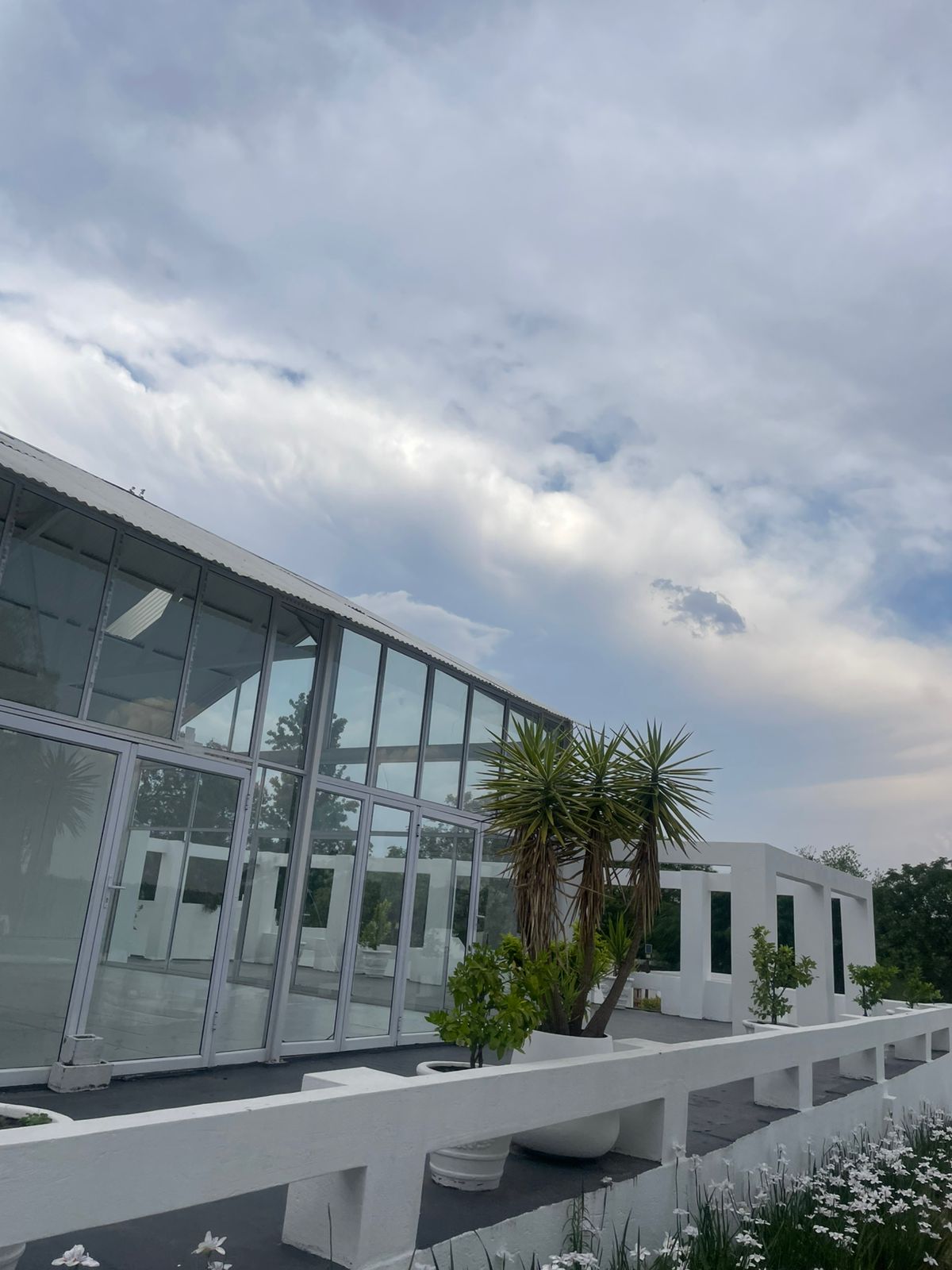 Glass-walled pavilion with cloud-streaked sky