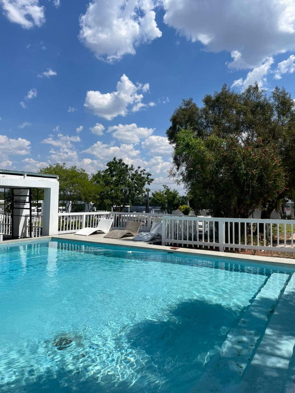 Crystal-clear pool with sun loungers and white picket deck